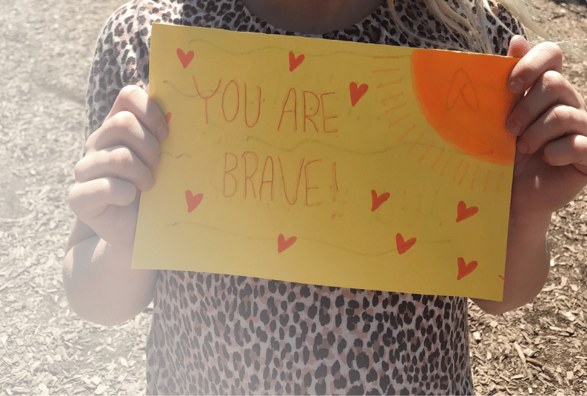 Yellow card that says "You Are Brave" on it being held by a girl